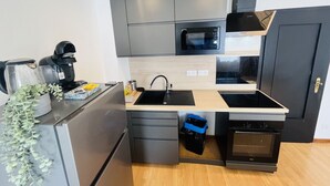Een kleine keuken met een magnetron, fornuis, spoelbak en koffiezetapparaat.