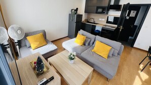 Een moderne woonkamer met een bank, salontafel en een klein keukentje met inbouwapparatuur.