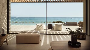 Una sala de estar moderna con un amplio ventanal corredera que da a un balcón con vistas al mar.