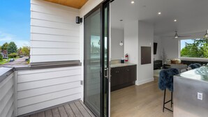 Une cuisine moderne avec des meubles de couleur sombre, une porte d’entrée en verre et une vue sur l’extérieur.