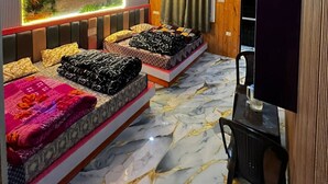Una habitación con paneles de madera, un mural, dos camas con ropa de cama estampada y un suelo de mármol.