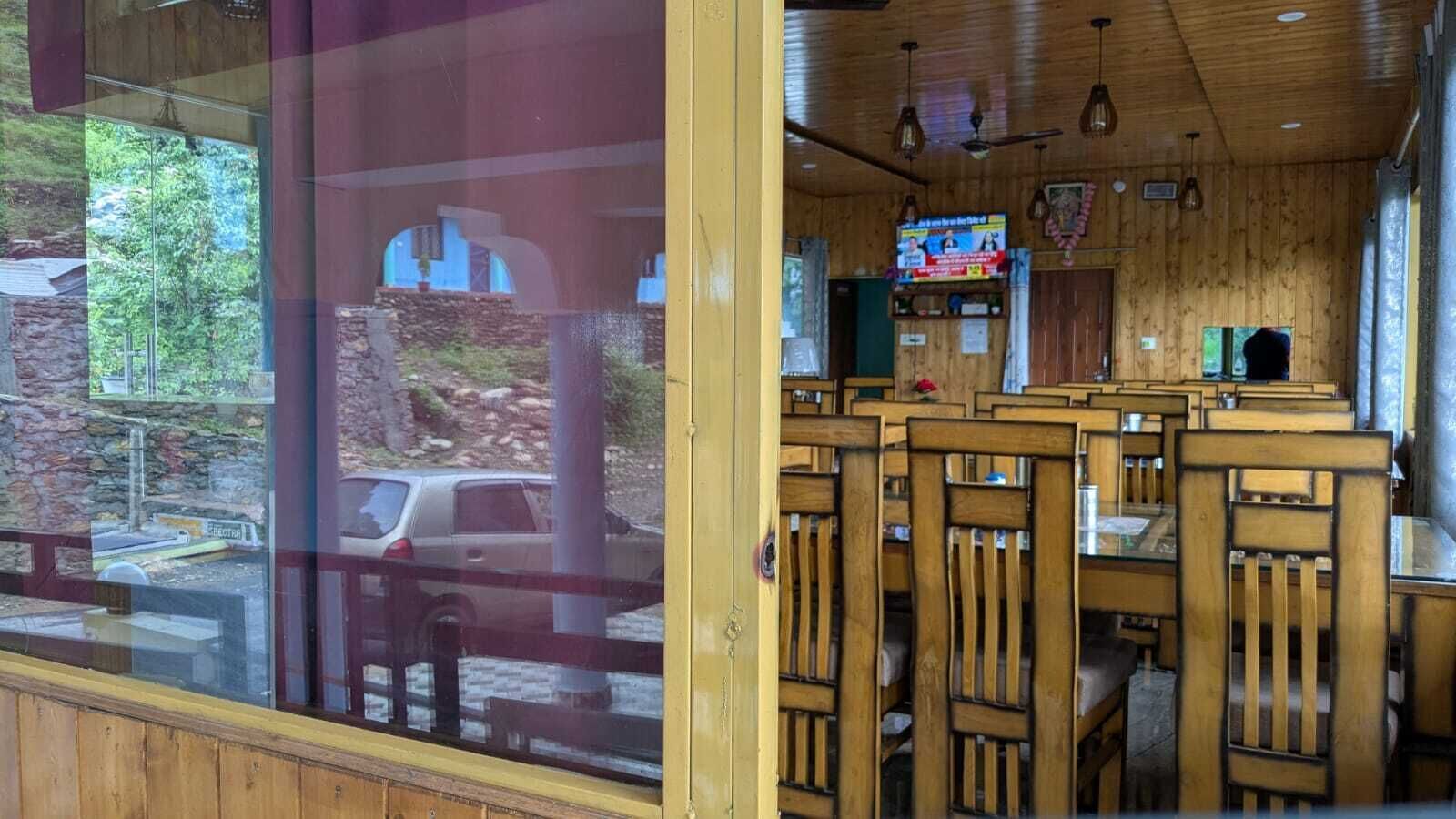 Ein Restaurant mit Holzvertäfelung, einem an der Wand befestigten Fernseher und Blick ins Freie durch große Fenster.