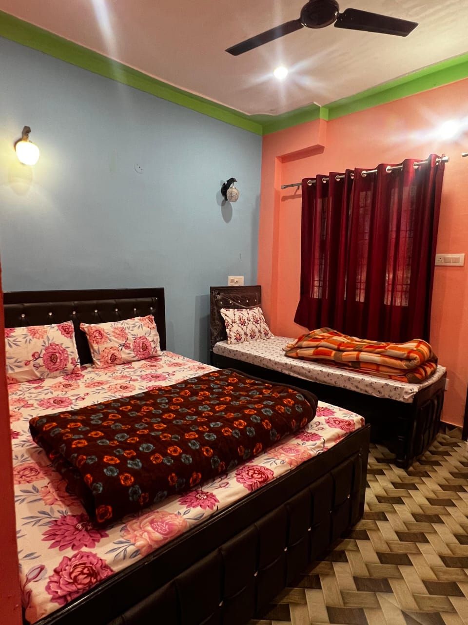 A bedroom with two beds, a ceiling fan, and a red curtain.