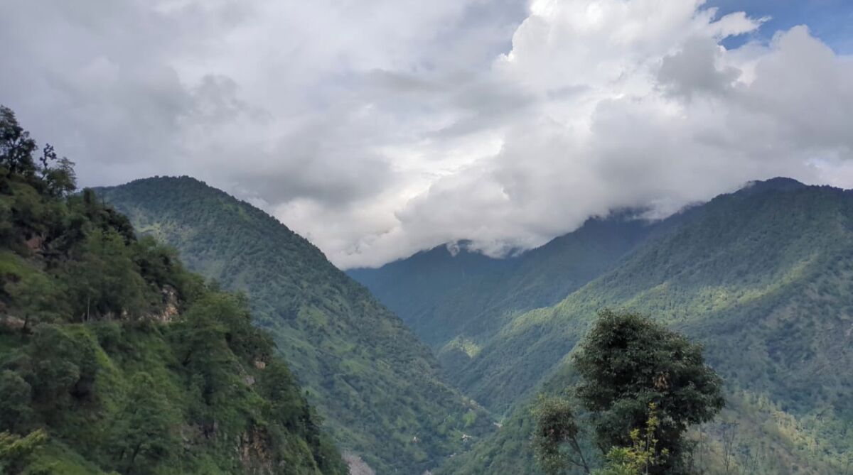 A mountainous landscape with dense greenery and a valley.
