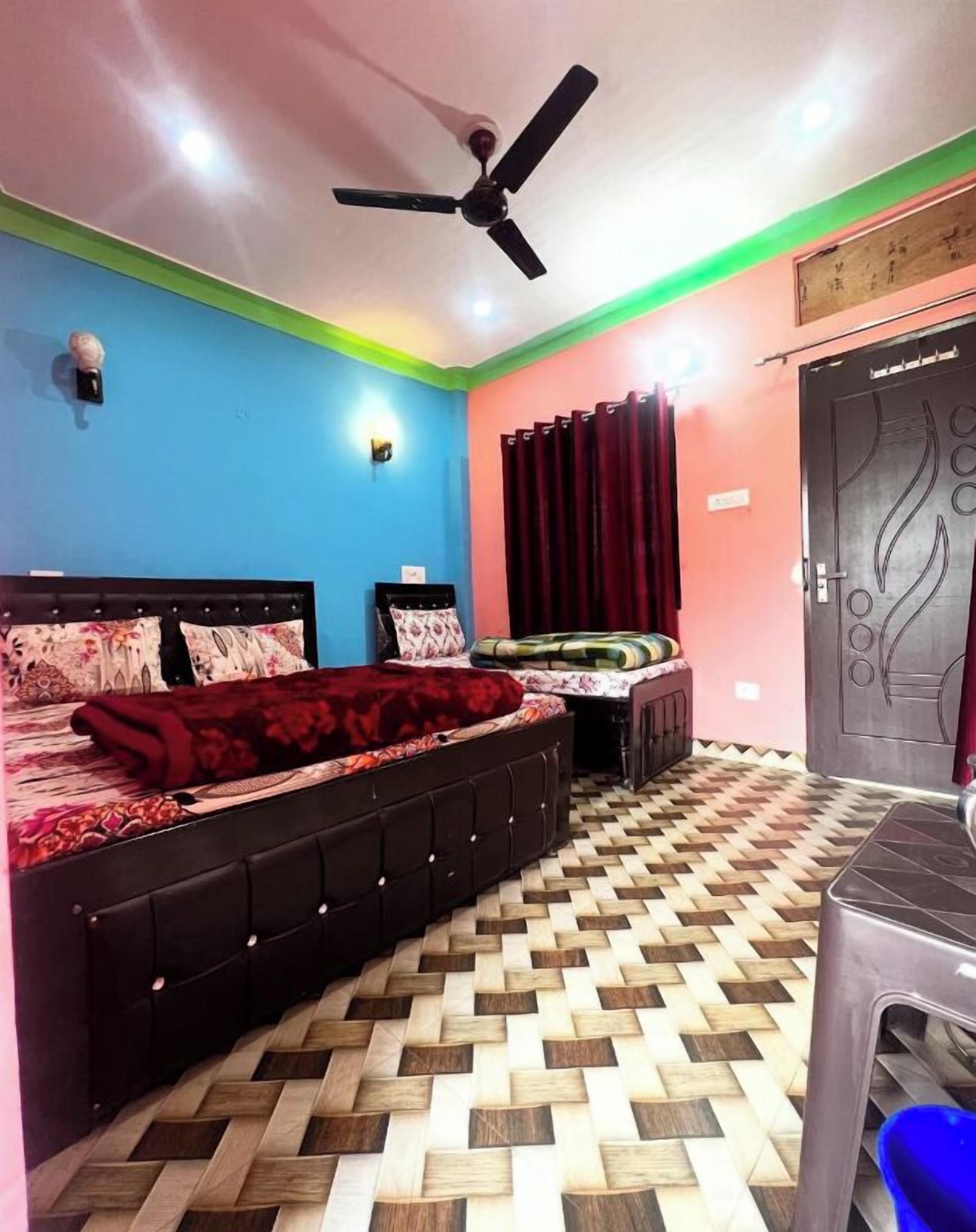 A bedroom with a bed, a desk, a chair, a ceiling fan, and a patterned floor.