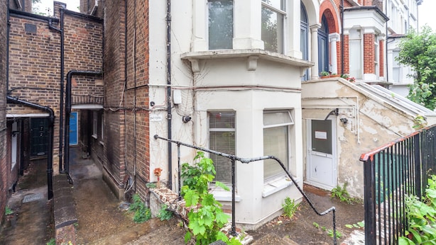 A narrow alleyway between two brick buildings with a white corner house. - The Ealing Villa (London)