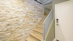A staircase with a stone wall, wooden steps, and a door with a keypad lock. - Gated Gainey Ranch condo, garage, heated pool, walk to restaurants, shopping! (Scottsdale)