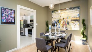 A dining area with a round table, grey chairs, and a large abstract painting on the wall. - Gated Gainey Ranch condo, garage, heated pool, walk to restaurants, shopping! (Scottsdale)