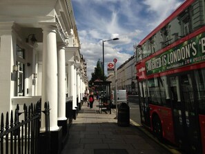 A street with a red double-decker bus, white buildings with columns, and a pedestrian crossing. - Lidos Hotel (London)