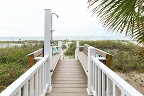 A wooden boardwalk leading to a beach with white railings and a showerhead. - 4 BR Oceanfront Beach House! Newly Renovated - Ocean Gem (Surfside Beach)
