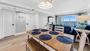 Een moderne, goed verlichte kamer met een houten eettafel, blauwe placemats en een hanglamp.