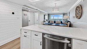 Een moderne keuken met witte kasten, een roestvrijstalen vaatwasser en een eethoek met uitzicht op de oceaan.