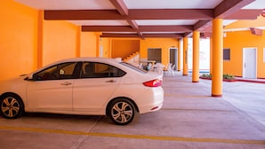 Een witte auto geparkeerd op een openbare parkeerplaats met oranje muren en een overdekte doorgang.
