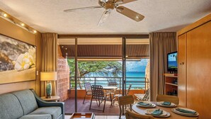 Una habitación de hotel con balcón, comedor, sofá y televisor.