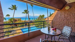 Un balcon avec vue sur une piscine, des palmiers et une plage.
