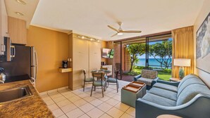 Una habitación de hotel moderna con cocina, comedor y un balcón con vistas al mar.