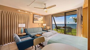 Habitación de hotel con cama, sofá, escritorio y vista al océano.