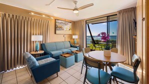 Una habitación de hotel moderna con sofá, sillas, una mesa de comedor y vista al océano.