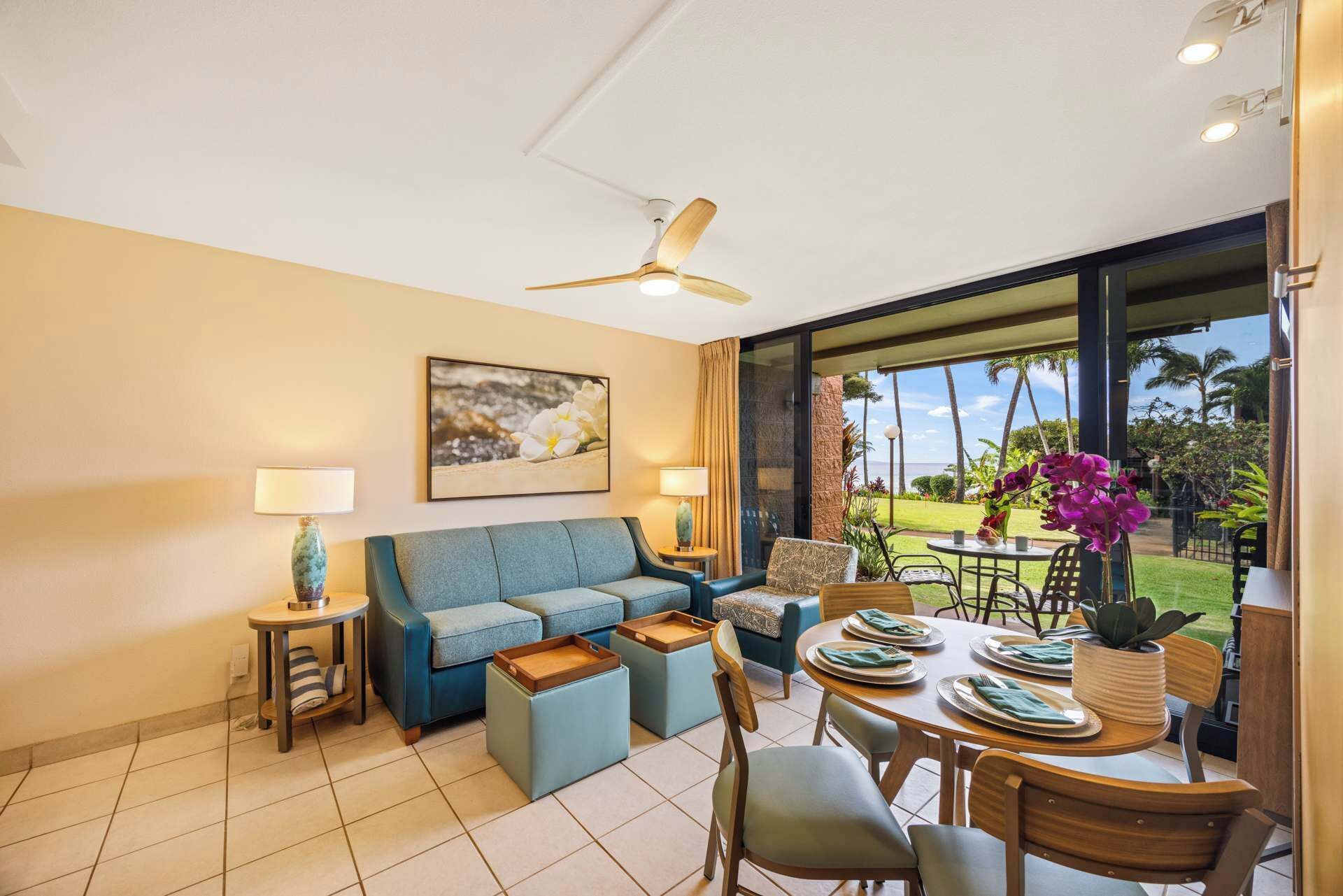 A modern living room with a blue sofa, a dining table set for four, and a view of the outdoors.