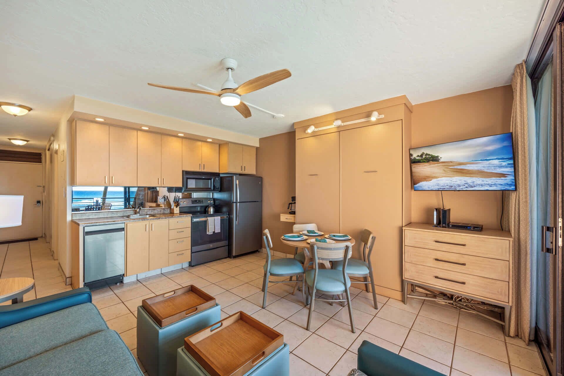 Una cocina moderna con comedor, ventilador de techo y televisor en la pared.