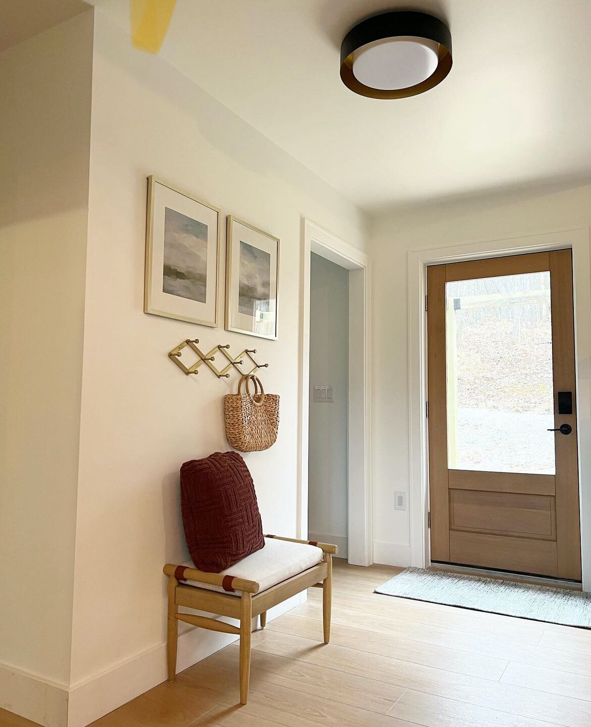 A hallway with a wooden bench, a door, and framed pictures on the wall.