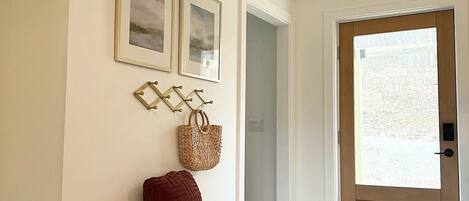 A hallway with a wooden bench, a door, and framed pictures on the wall.