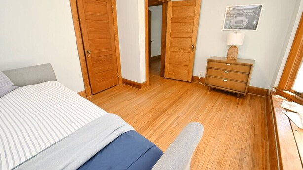 A bedroom with a bed, a dresser, and a door leading to another room. - Historic/Renovated home steps to Notre Dame(103) (South Bend)