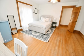A bedroom with a bed, bedside table, and a wooden floor. - Historic/Renovated home steps to Notre Dame(103) (South Bend)