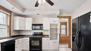 A kitchen with white cabinets, a black stove, and a black refrigerator. - Historic/Renovated home steps to Notre Dame(103) (South Bend)