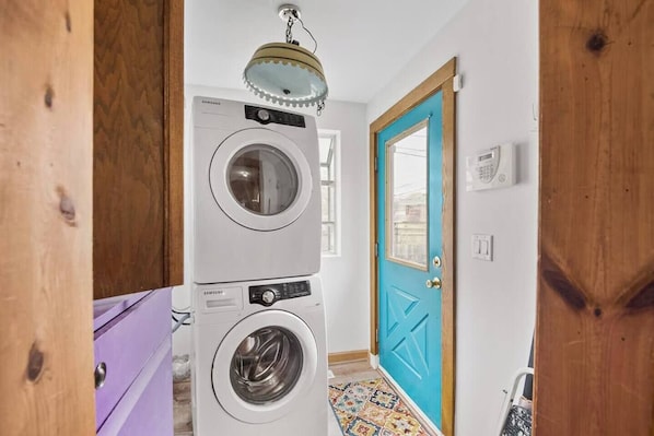 Un área de lavandería con lavadoras apiladas, una puerta con marco azul y un piso con diseño.