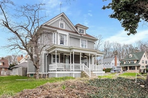A two-story house with a front porch, a chimney, and a well-maintained lawn.