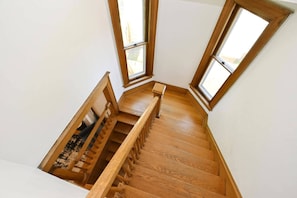 Una escalera de madera con barandilla que lleva a una plataforma con vistas al exterior.