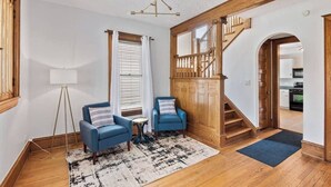 A living room with a staircase, two blue armchairs, a floor lamp, and a rug. - Historic/Renovated home steps to Notre Dame(103) (South Bend)