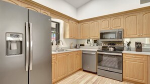 Une cuisine moderne dotée d’appareils électroménagers en acier inoxydable, de meubles en bois et d’un distributeur d’eau.
