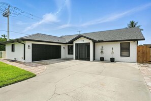 A two-story house with a garage, a driveway, and a well-maintained lawn. - Sunny Pool Retreat, Pet-Friendly Near Beaches (Naples)
