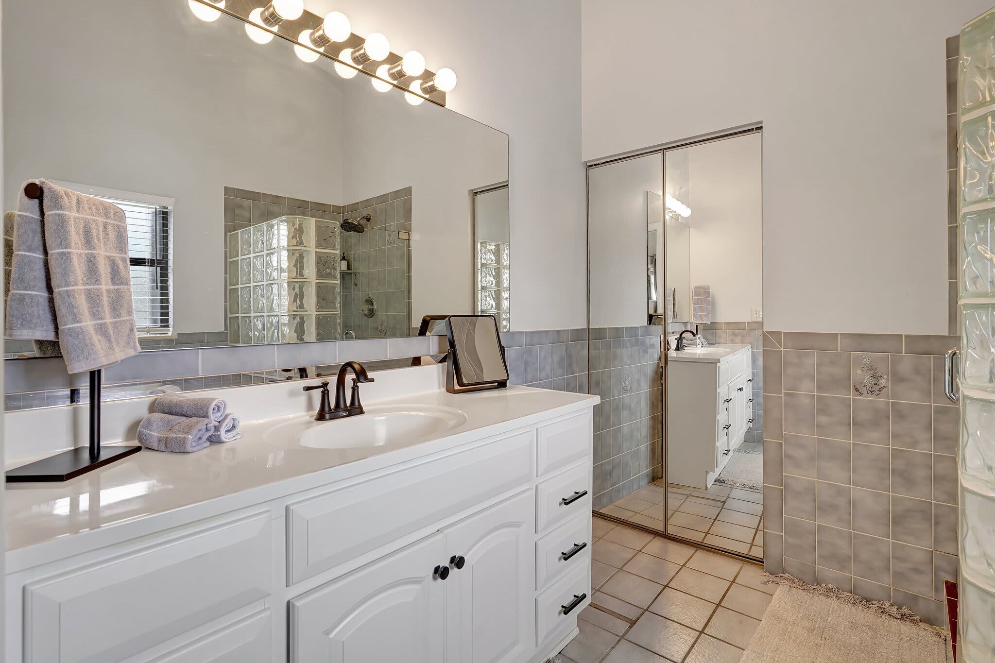 Une salle de bain moderne avec un meuble-lavabo, un grand miroir et un espace douche.