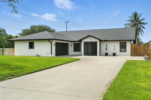 A two-story house with a garage, a covered front porch, and a number "98" on the front door.