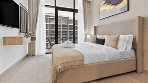 Une chambre d’hôtel moderne dotée d’un grand lit, d’une télévision à écran plat, d’une grande fenêtre avec des rideaux et offrant une vue sur la ville.