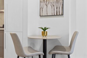 A small round table with two chairs, a potted plant, and a framed picture on the wall. - Waves - Azizi Riviera Building 25 Cozy Studio With Balcony (Dubai)