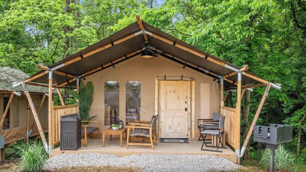 Eine Holzhütte mit Satteldach, einer Tür und einer Veranda mit zwei Stühlen und einem Tisch.
