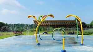 Ein Spielplatz im Freien mit bunten Klettergerüsten und einer überdachten Sitzgelegenheit.