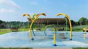 An outdoor playground with colorful climbing structures and a covered seating area.