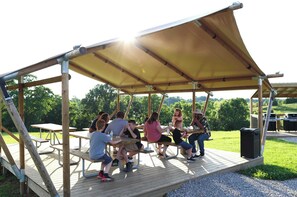 A wooden deck with picnic tables and a canopy.