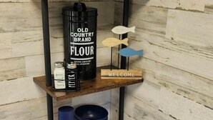A wooden shelf with various items including a bottle of wine, salt and pepper shakers, a welcome sign, and decorative fish figures. - Property of Big Foot Roscoe, NY (Roscoe)