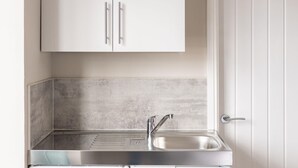 A kitchen with a stainless steel sink, a single cabinet, and a white door. - Host & Stay | Clifton Studio 2 (Darlington)