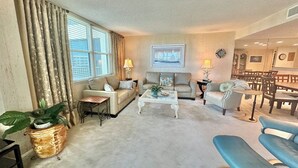A living room with a sofa, armchairs, a coffee table, and a dining area with chairs and a table. - Gulf and Bay Club B604 (Siesta Key)