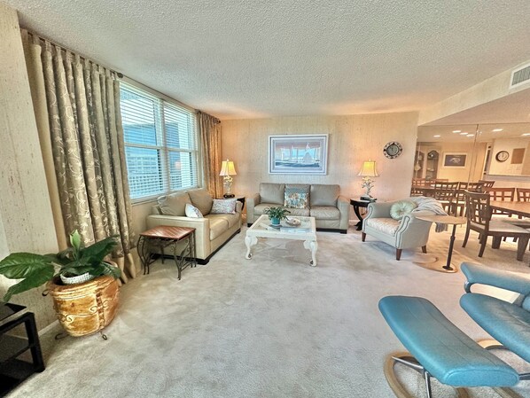 Un salon comprenant un canapé, des fauteuils, une table basse et un coin repas avec des chaises et une table.