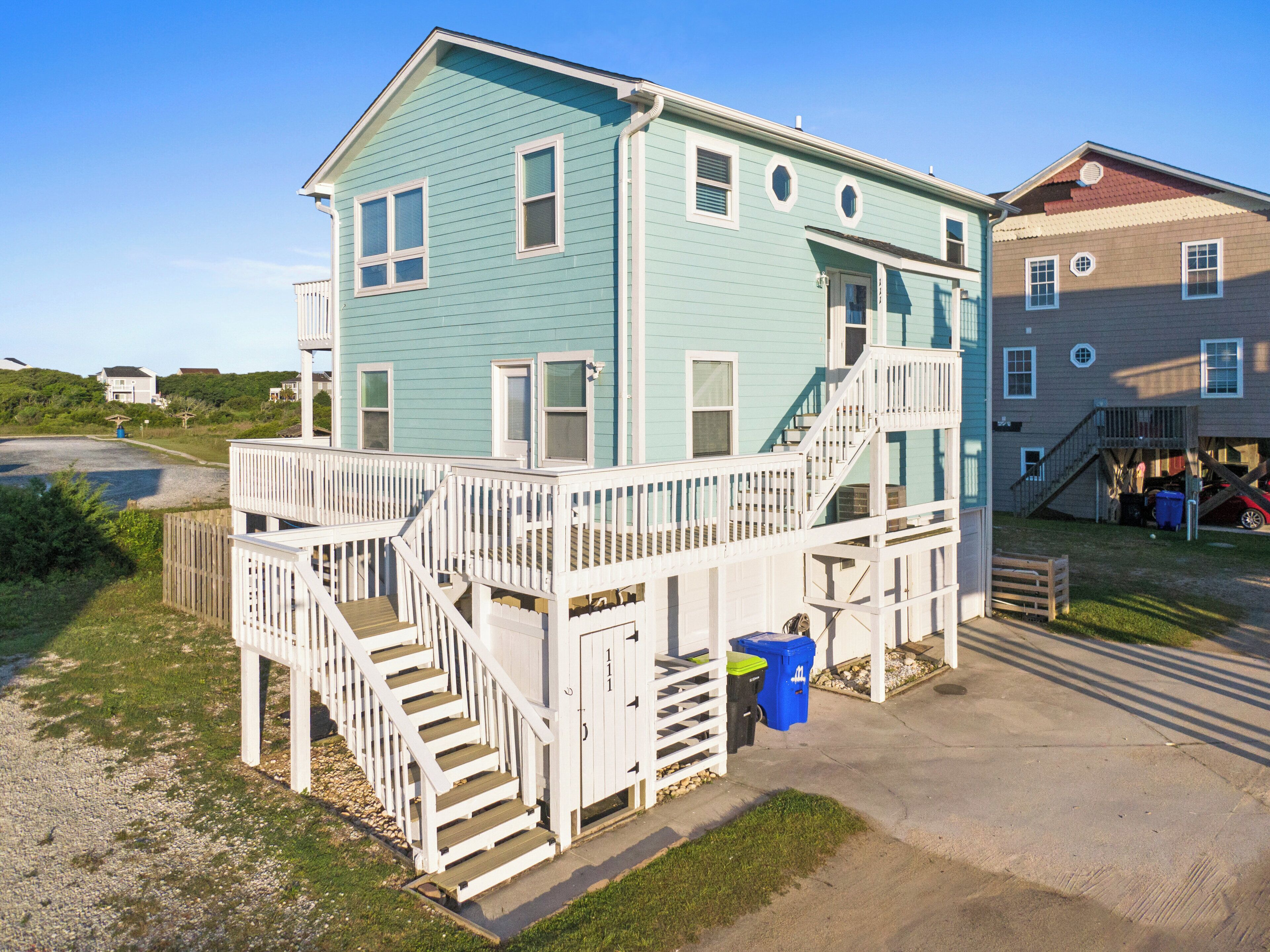 A two-story house with a wooden deck and stairs leading to the second floor.