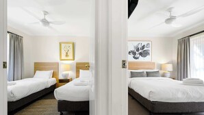 A hotel room with two beds, a ceiling fan, a framed floral artwork, and a patterned rug. - Melview Greens - Two-Bedroom Apartment (Orange)
