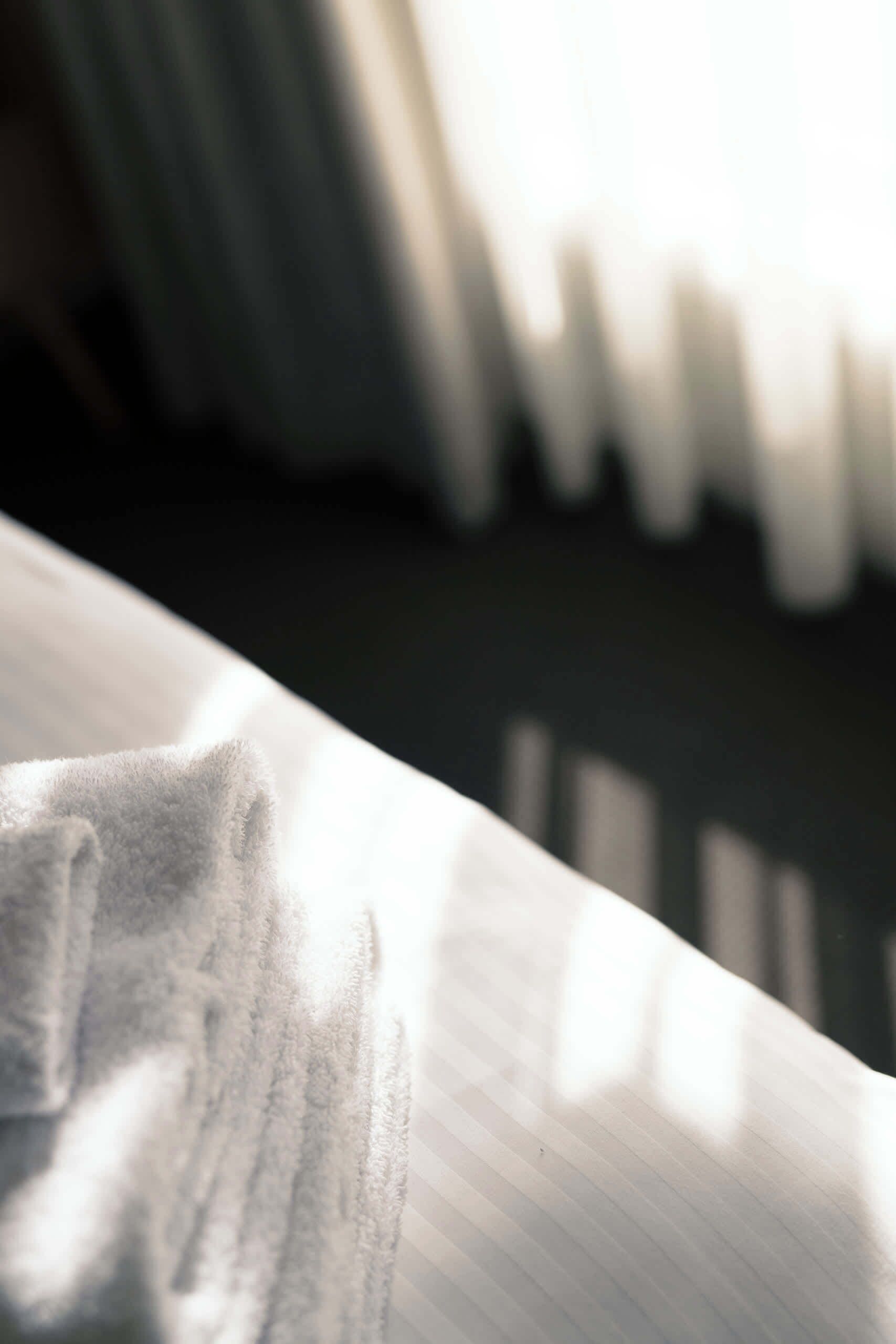 A close-up of a white, textured surface with a soft, plush texture, likely a part of a bed or sofa.